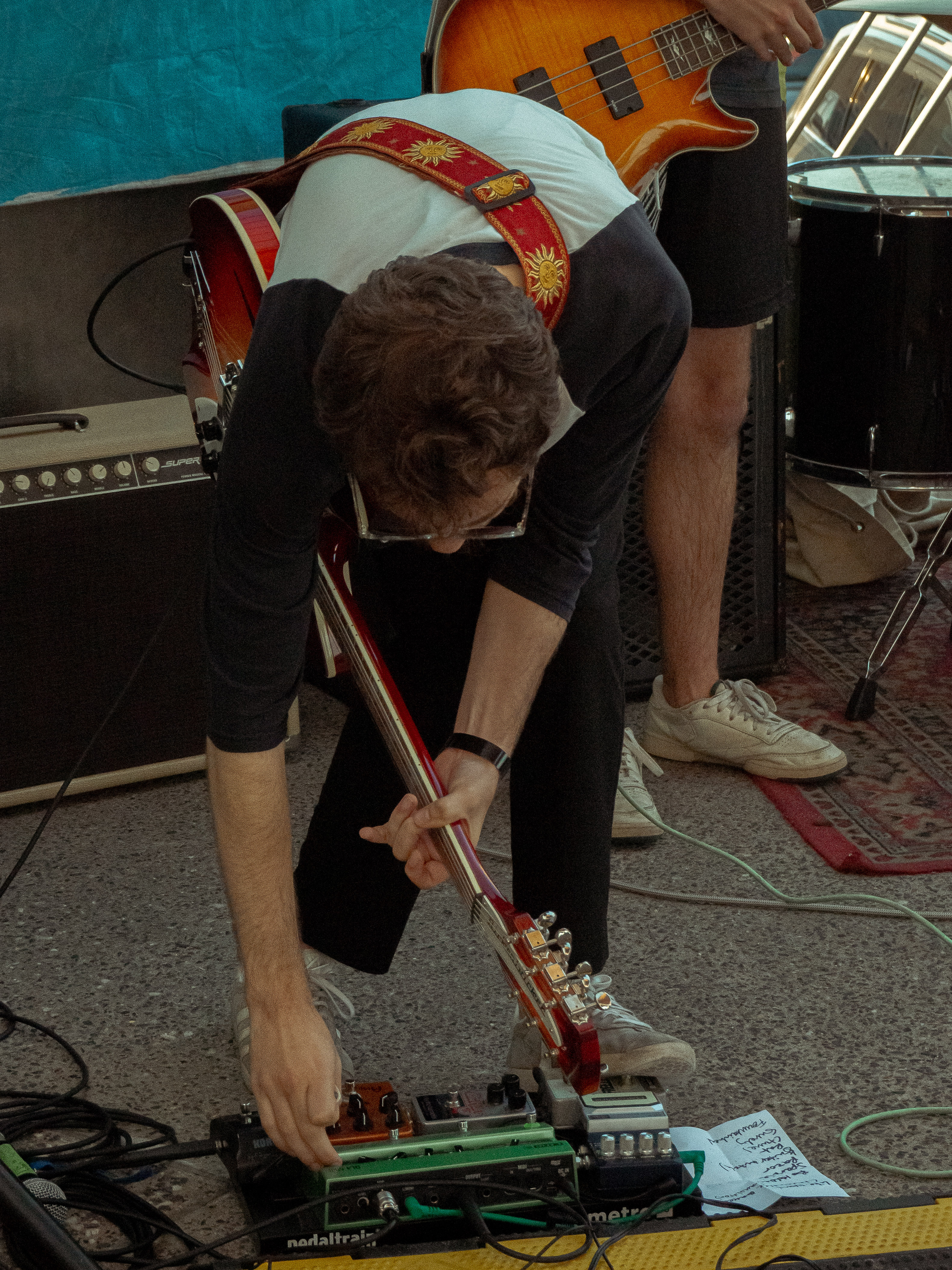 Guitarist, Trevor, leans over pedal board