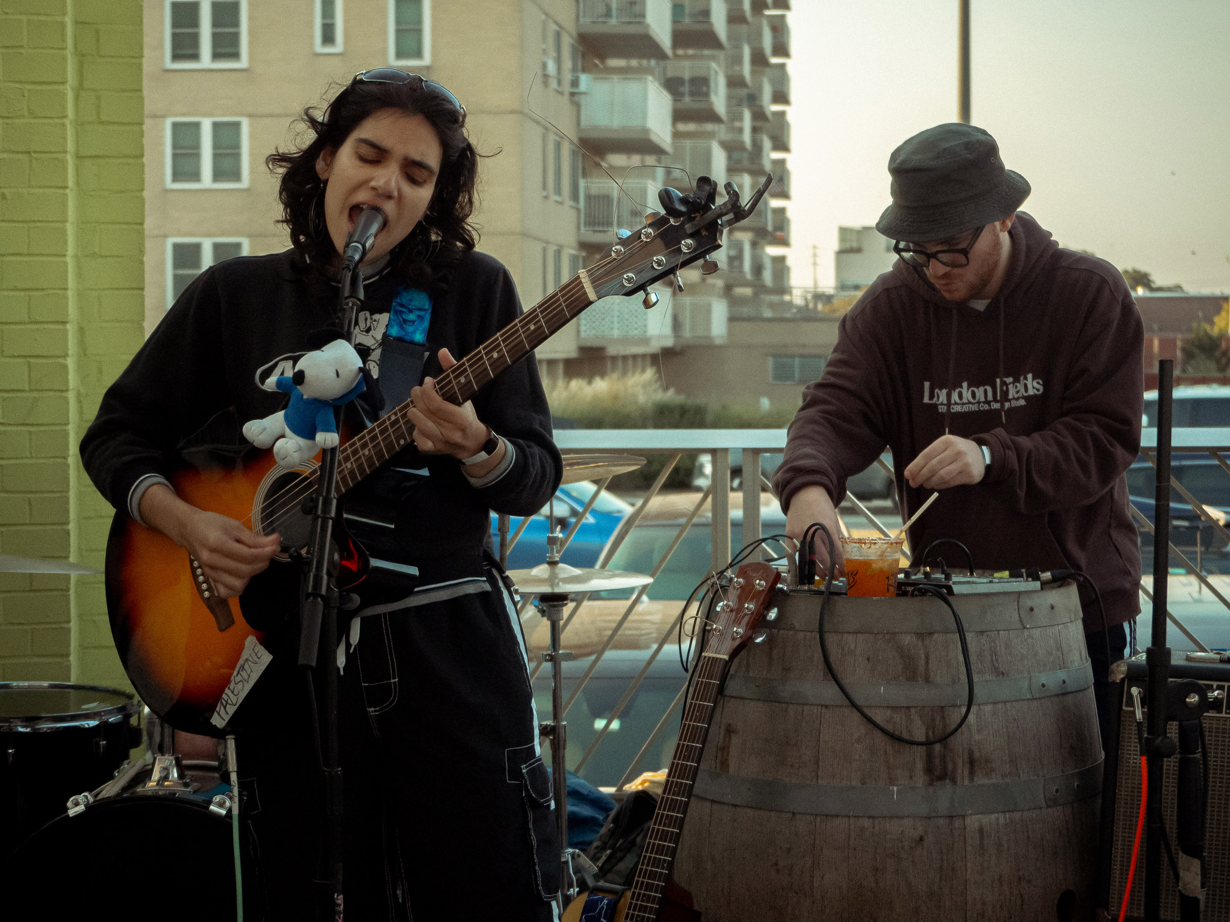 Nara plays guitar and sings beside Will and his pedal-barrel.