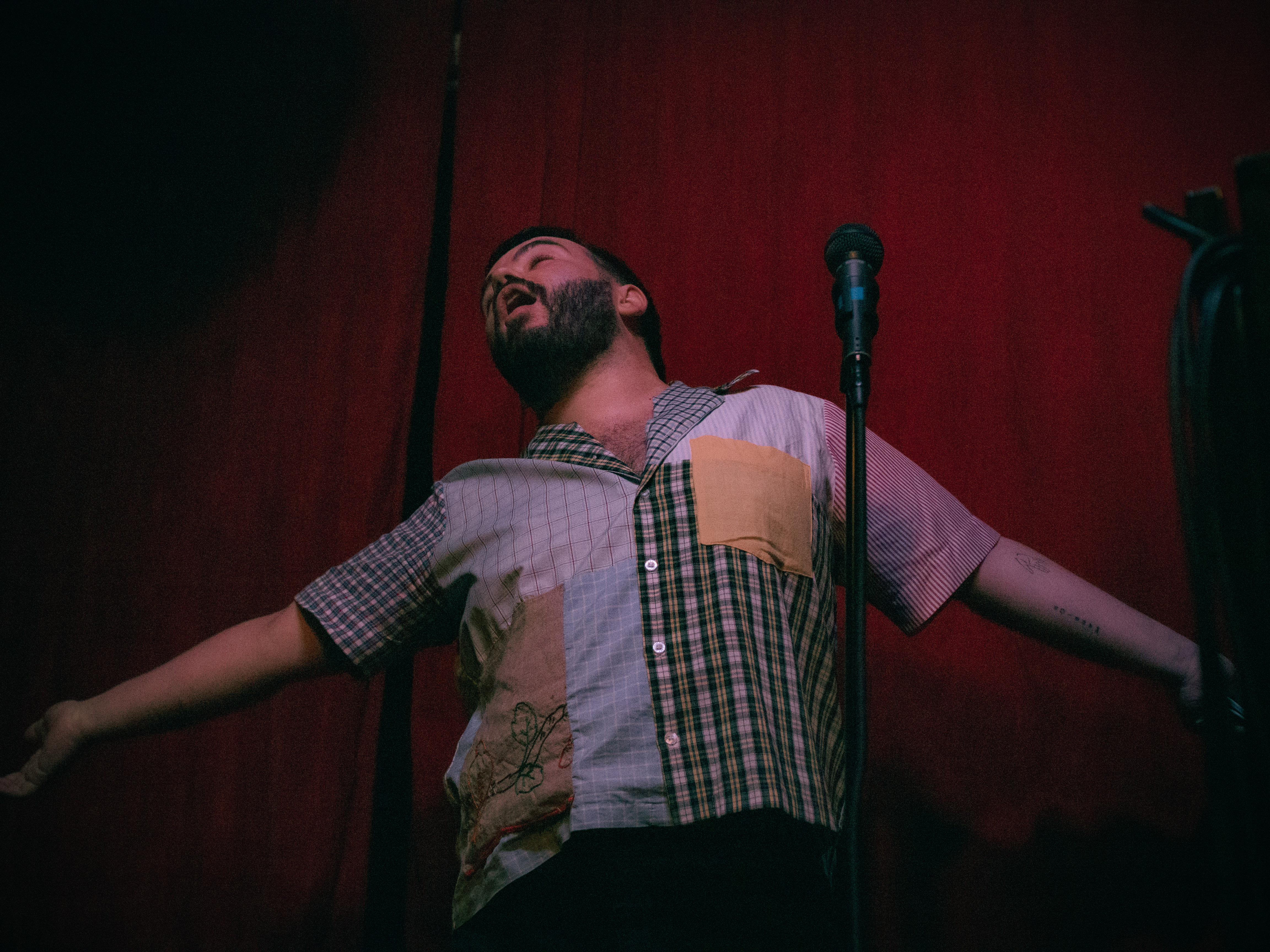 Comedian Patrick Howard spreads arms and sings to the celing.