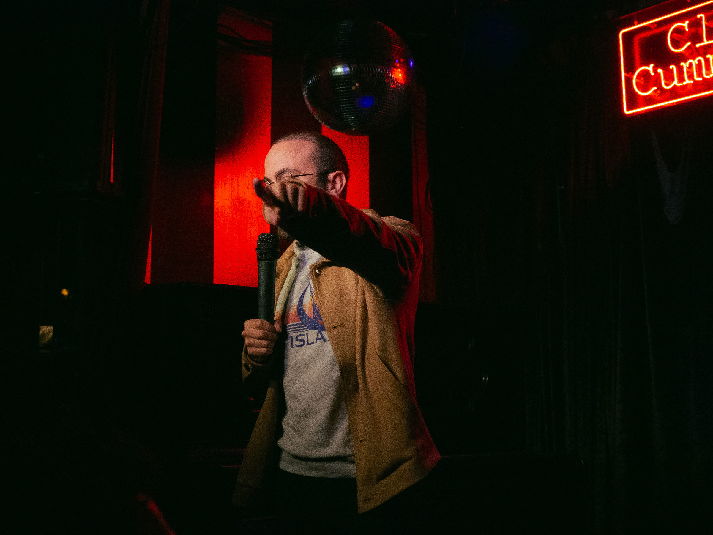 Gus Constantellis obscures face with hand while pointing at audience.